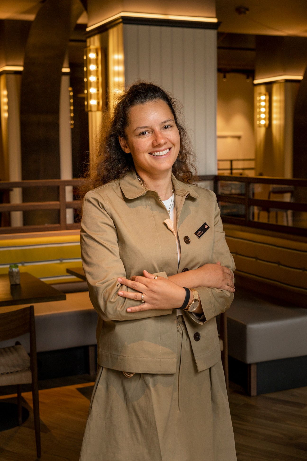 Breakfast supervisor Emira smiling in hotel uniform with arms crossed