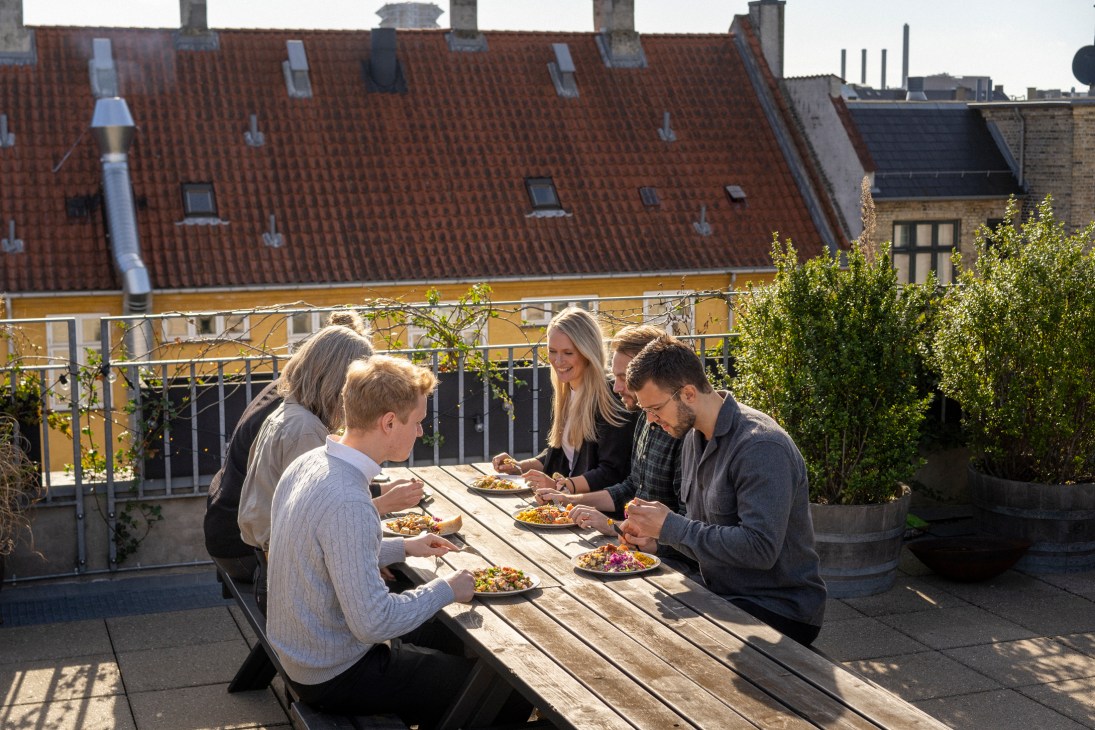 Podimo employees dining together on a rooftop terrace in Copenhagen with city views.