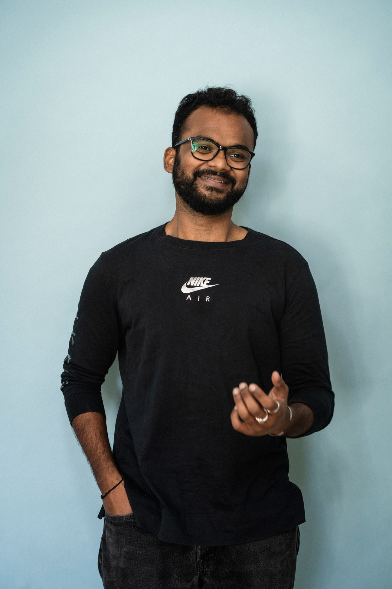 Product analyst Sameer Agarwal smiling at camera in black Nike Air shirt and glasses.