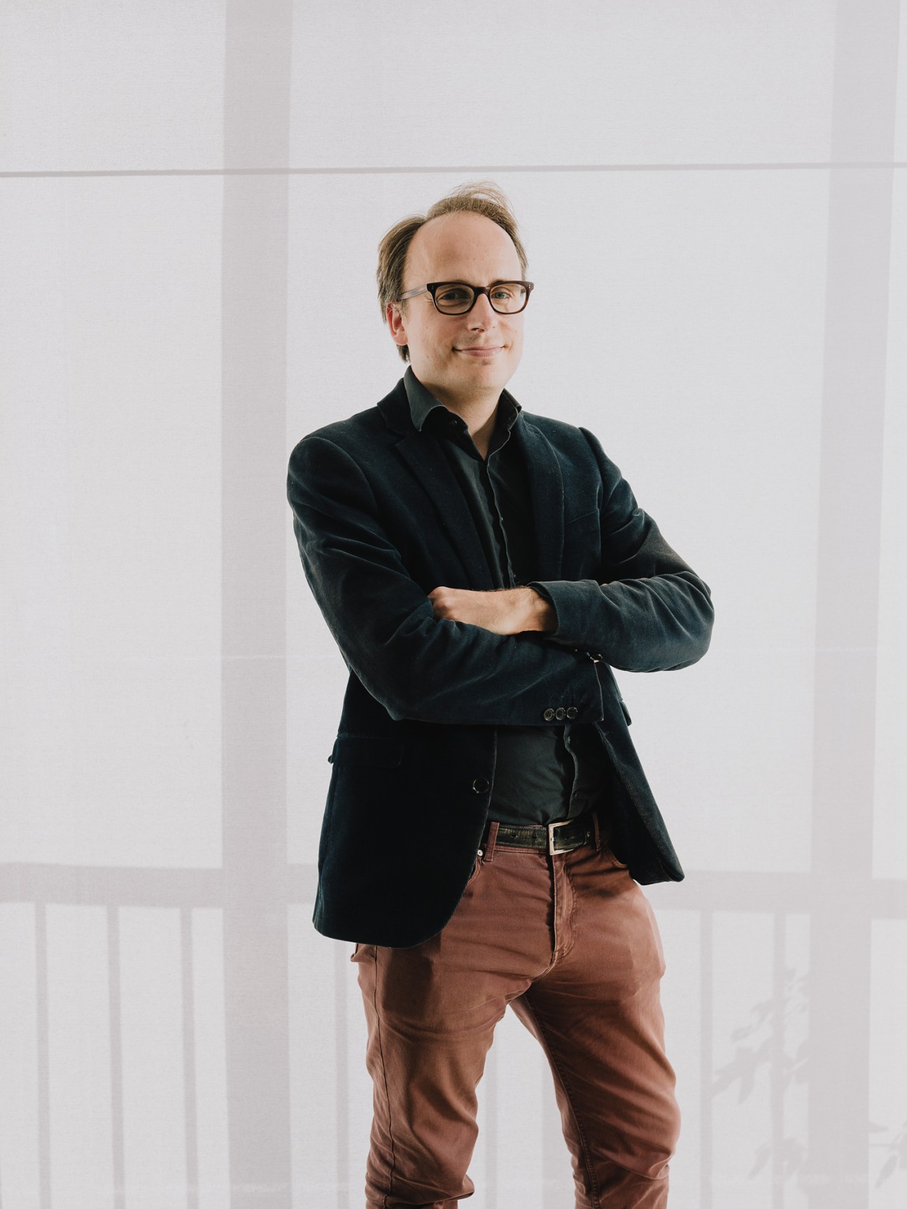 Benoît Sanson, architect at 31/44 Architects, stands with arms crossed wearing glasses and a dark blazer.