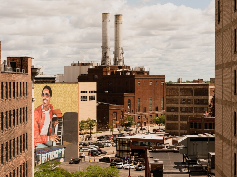 Large colorful mural of Stevie Wonder on yellow brick building wall in Detroit downtown urban area