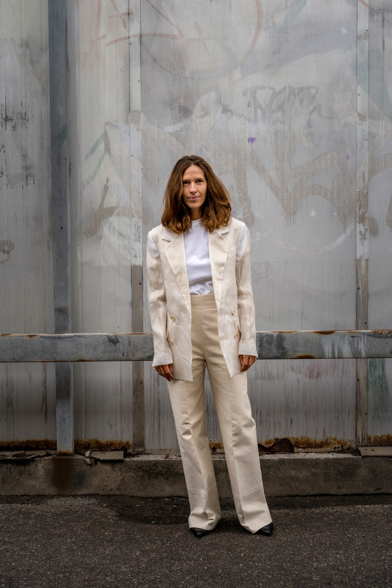 Nanna Hjortenberg standing against graffitied wall wearing beige blazer and trousers