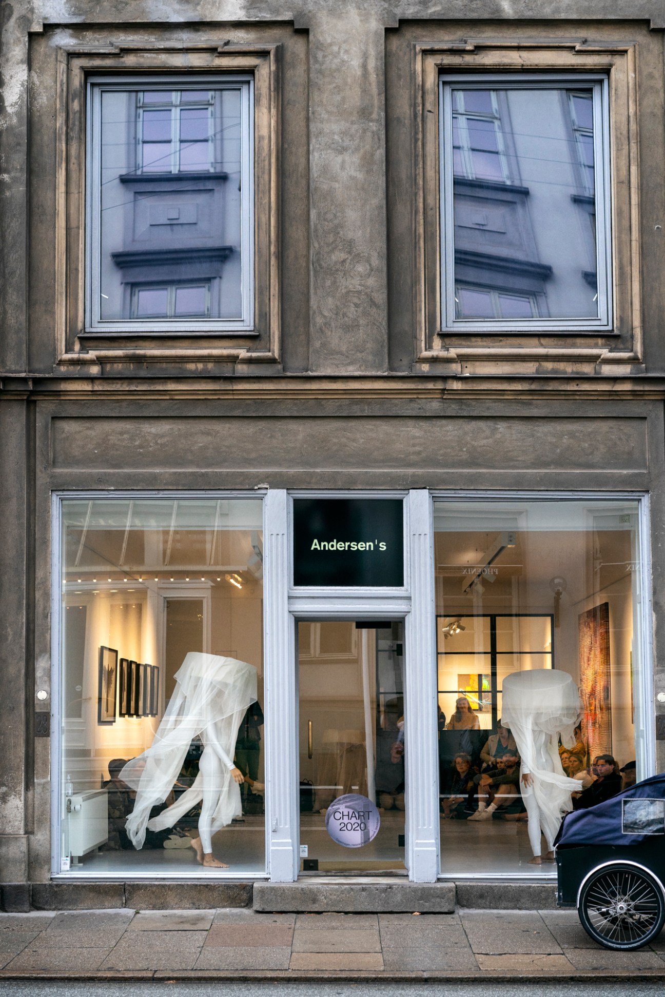 Performance artist in flowing white dress outside Andersen's gallery storefront in Copenhagen