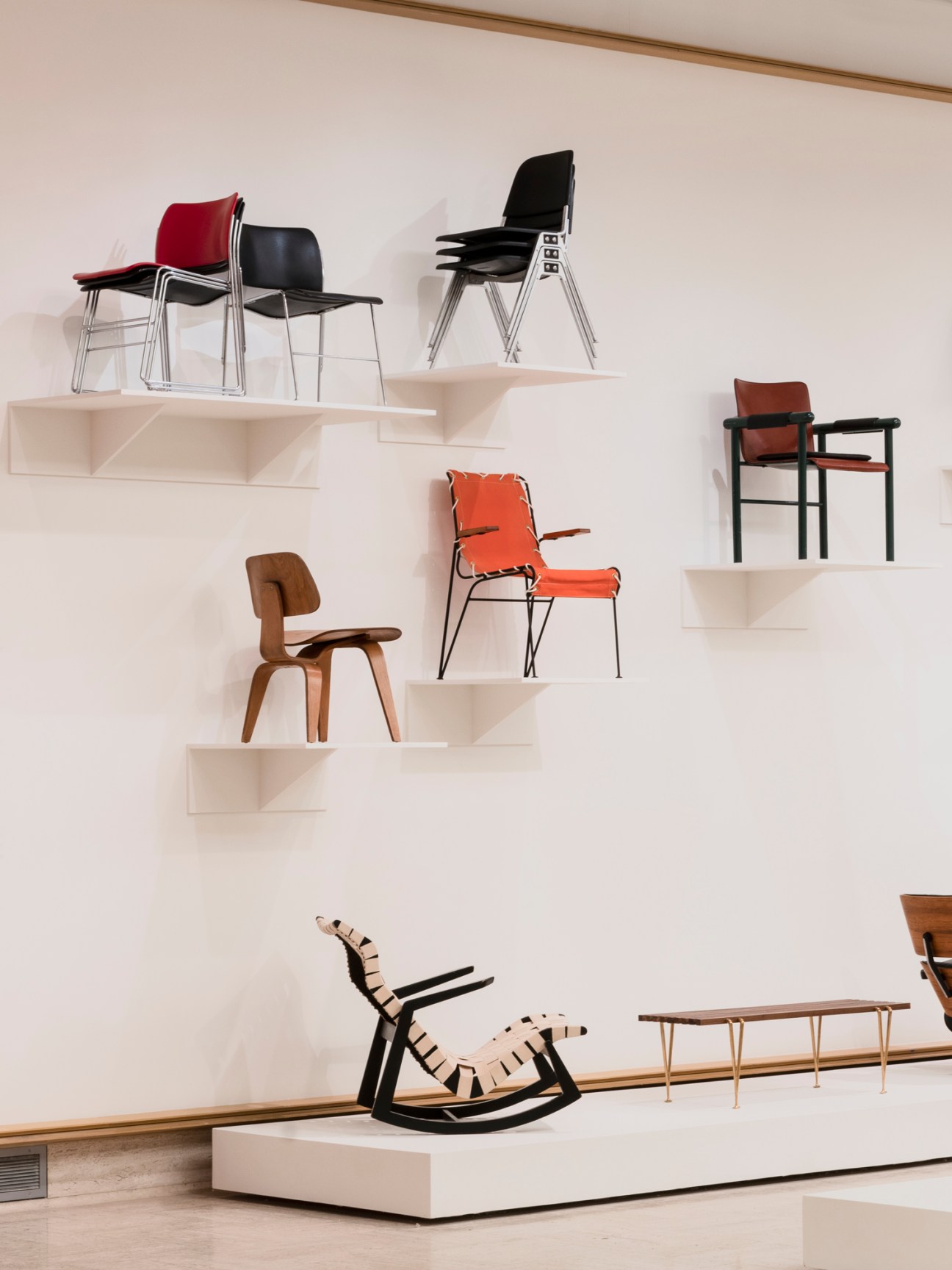 Display of modern chairs arranged on white floating shelves against a white wall