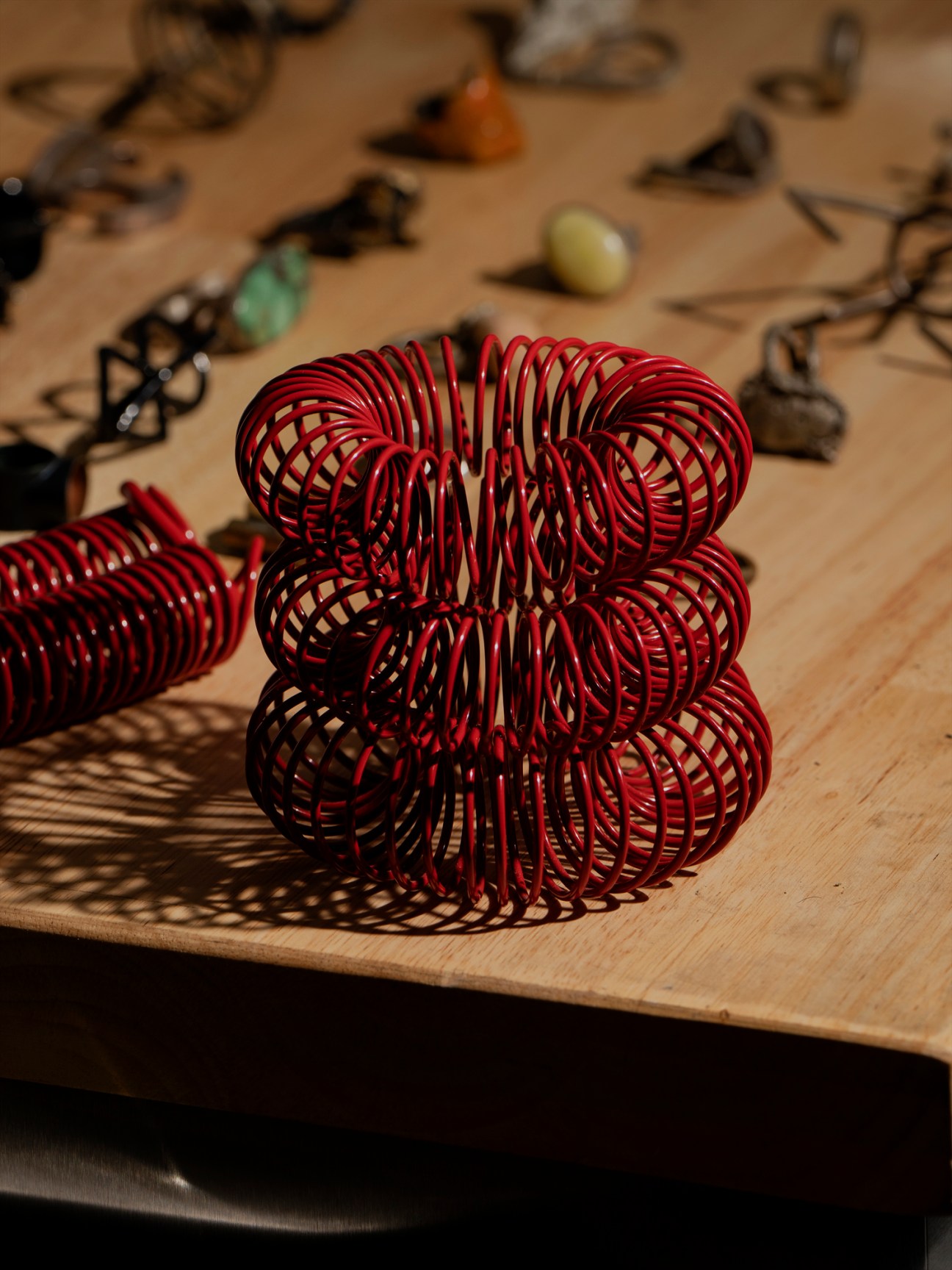 Red wire sculptural artwork created by artist Tiff Massey displayed on wooden surface