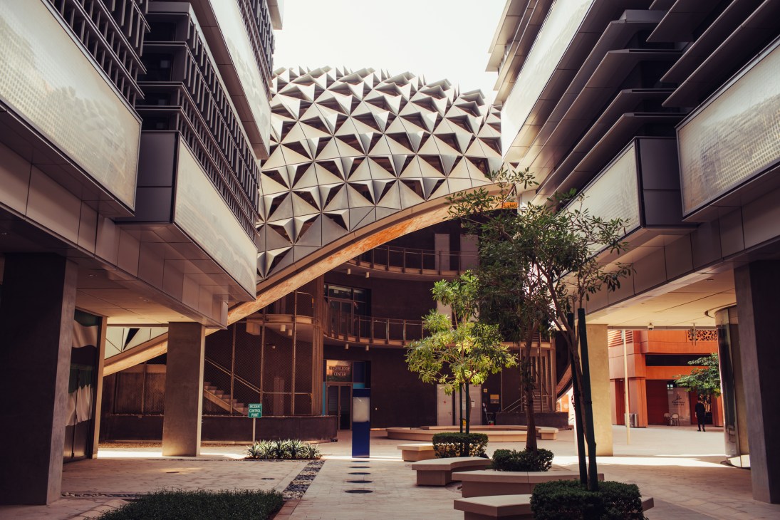 Shaded courtyard in Masdar City with geometric patterned ceiling, planters, and modern architecture.
