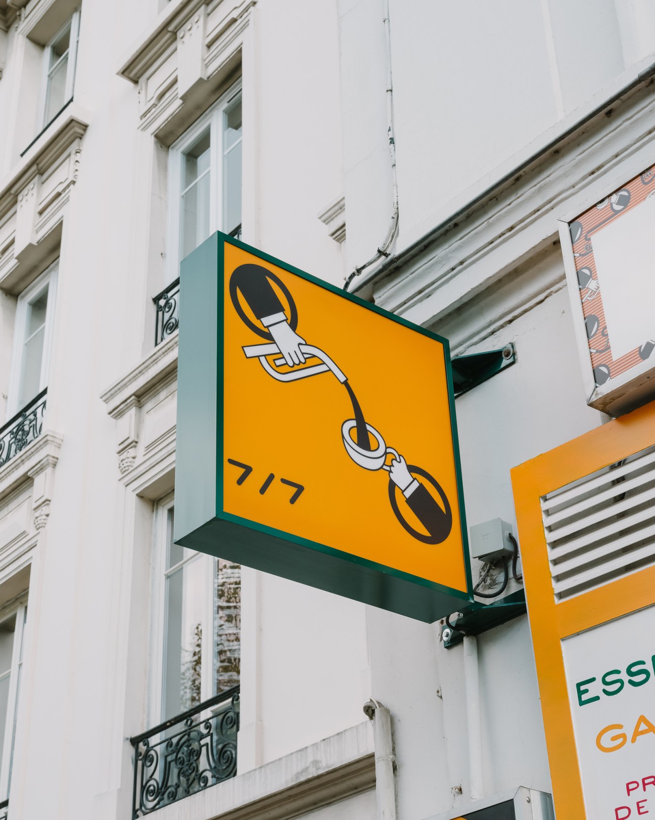 Orange and green sign with chain link design and number 717 mounted on white building exterior