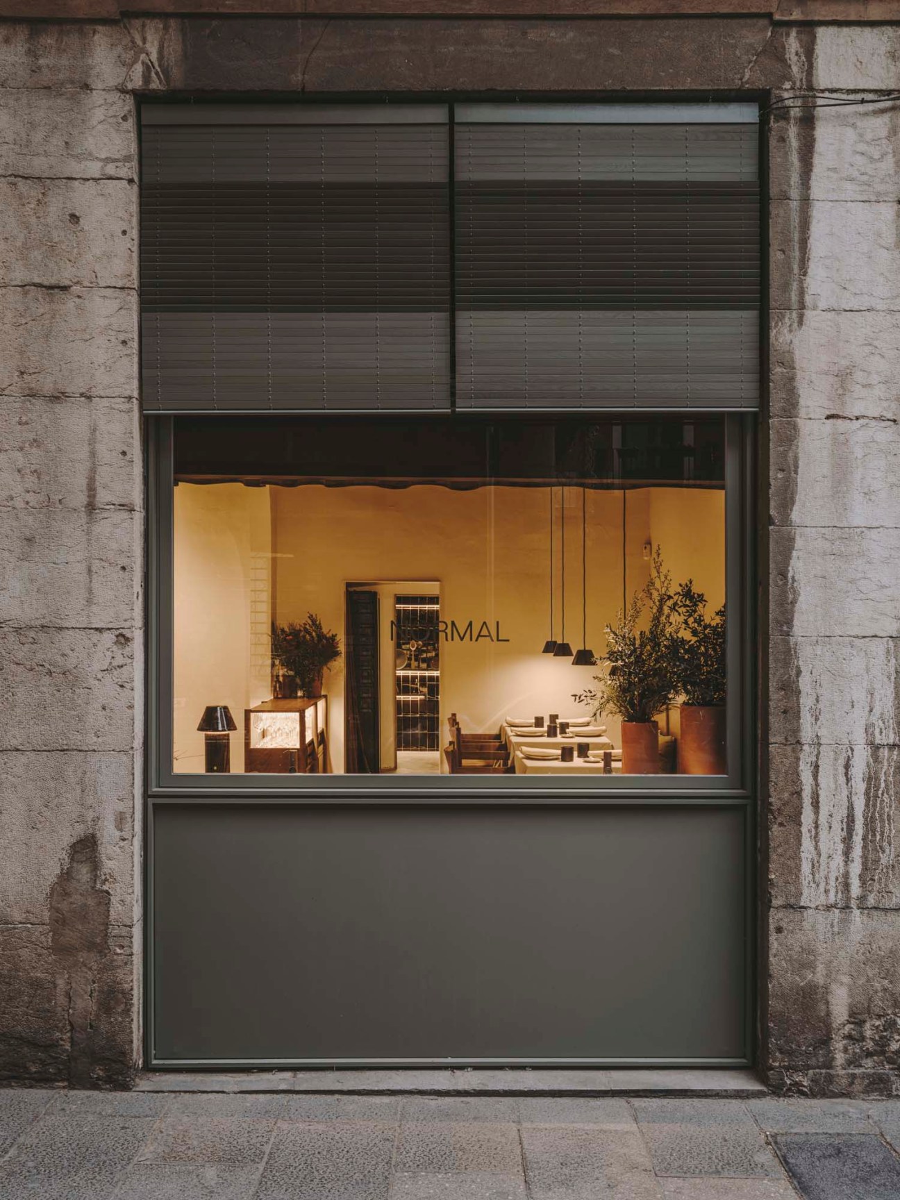 Storefront window view of Normal restaurant showing interior dining space with warm lighting and minimalist design