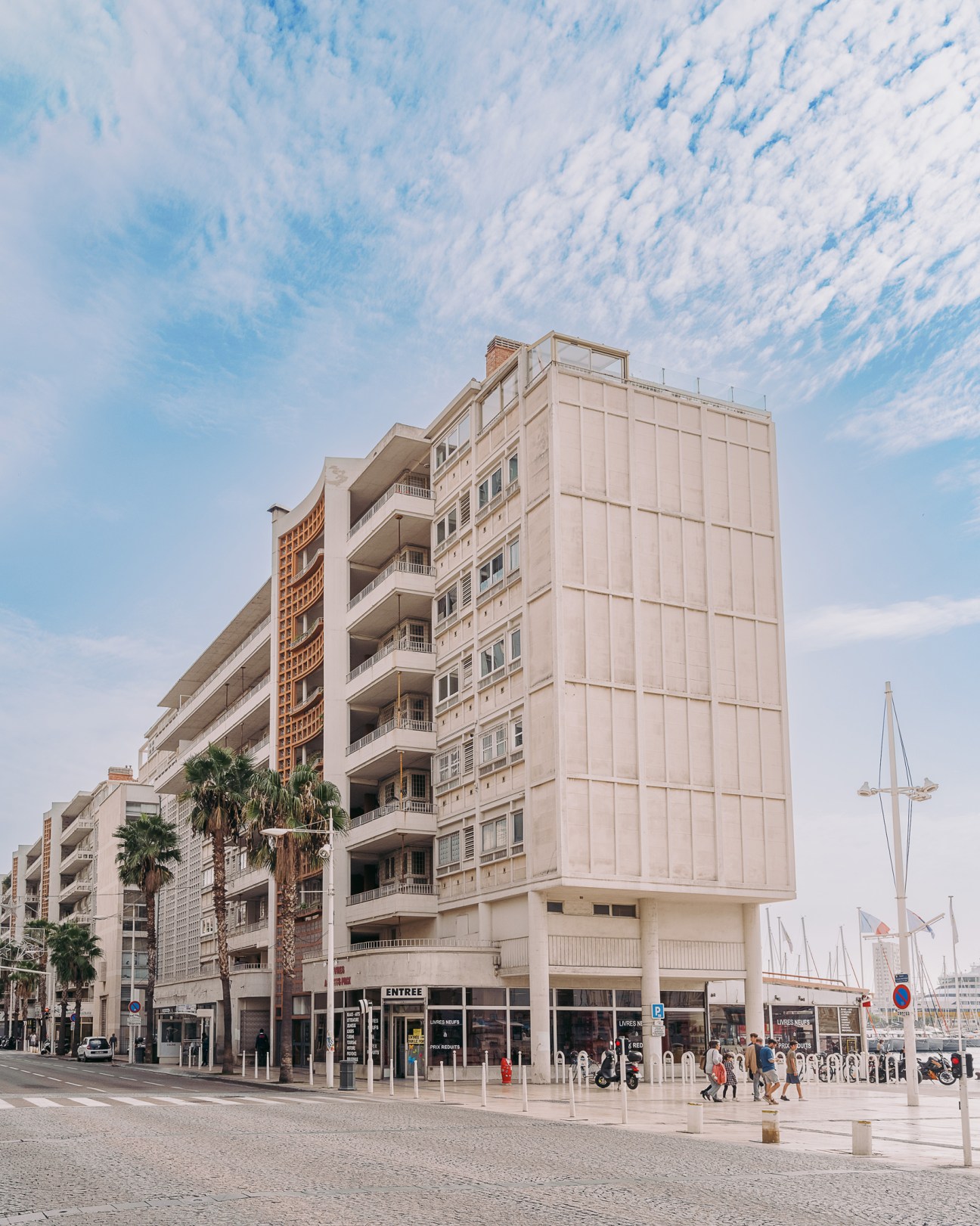 Beige multi-story residential building with balconies and retail storefronts at street level in Toulon, France.