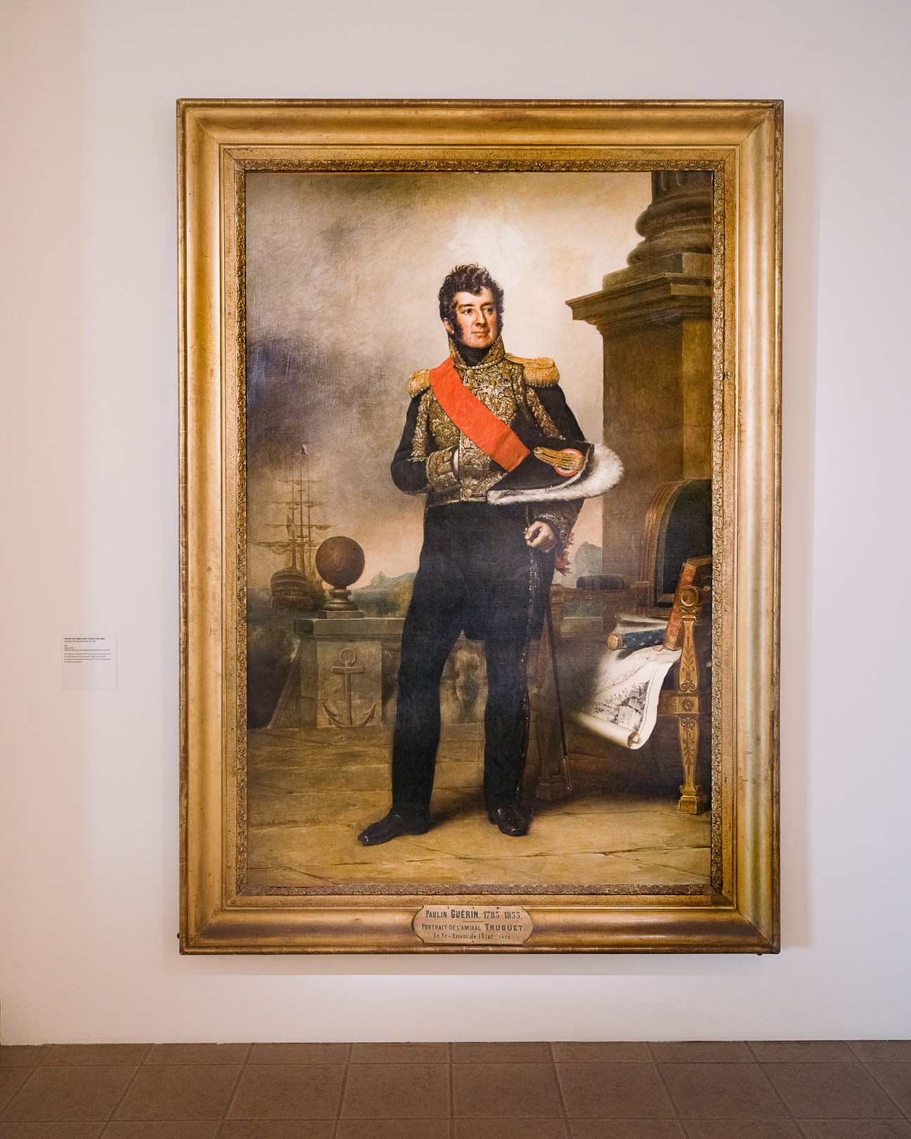Formal portrait painting of a military officer in 19th-century dress uniform with red sash, displayed in a gold frame.