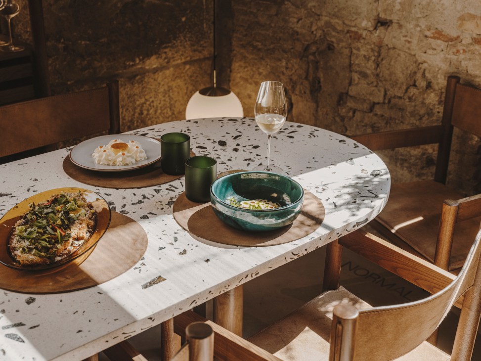 Normal restaurant dining area with round white speckled table set with dishes and wine glass