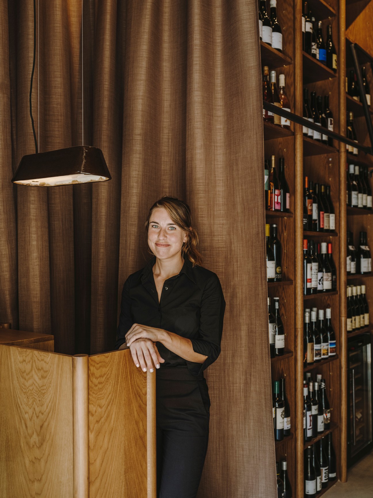 Woman in black shirt standing next to wine shelves in restaurant Normal in Girona