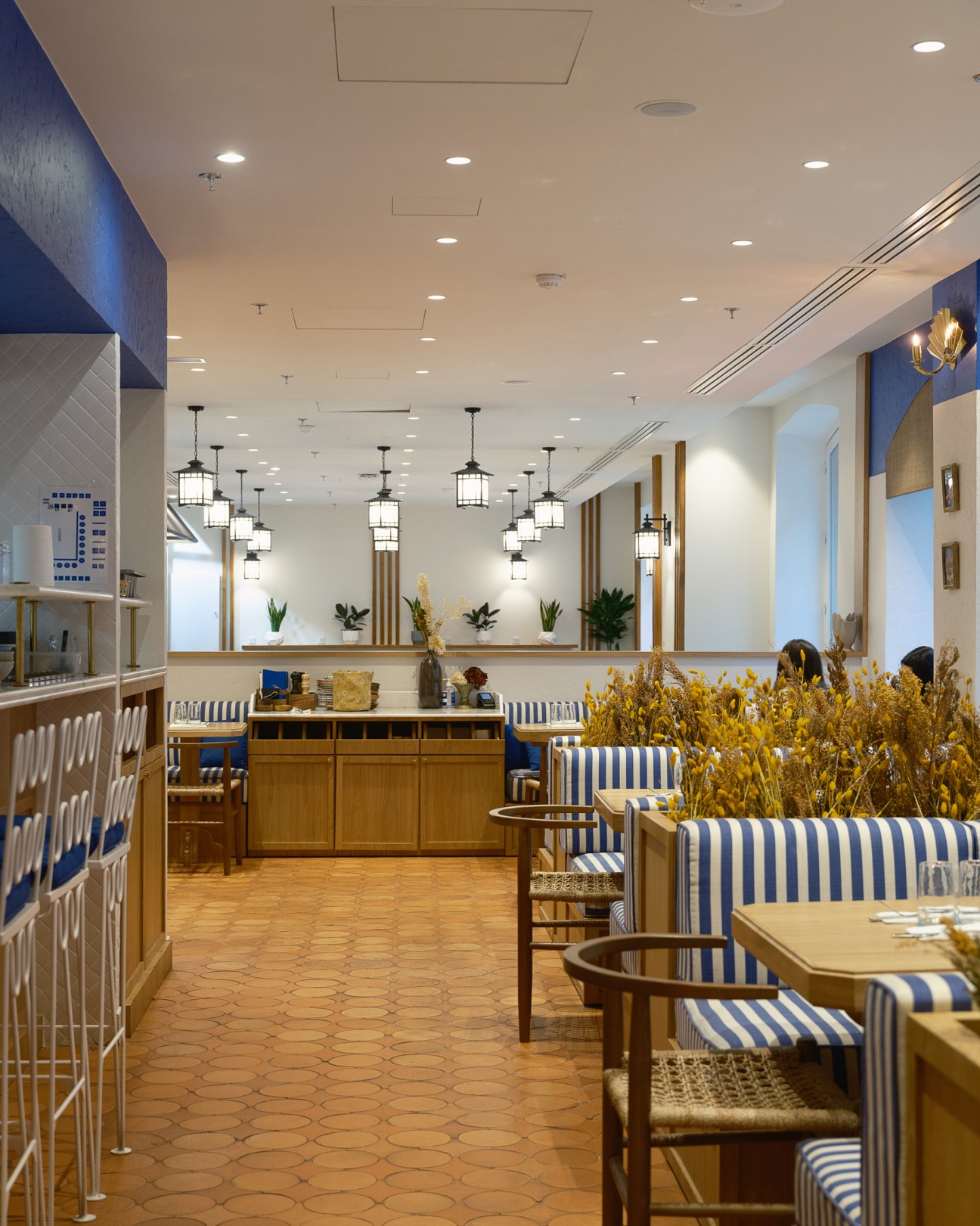 Modern restaurant interior with blue and white striped seating, hexagonal floor tiles, and pendant lighting