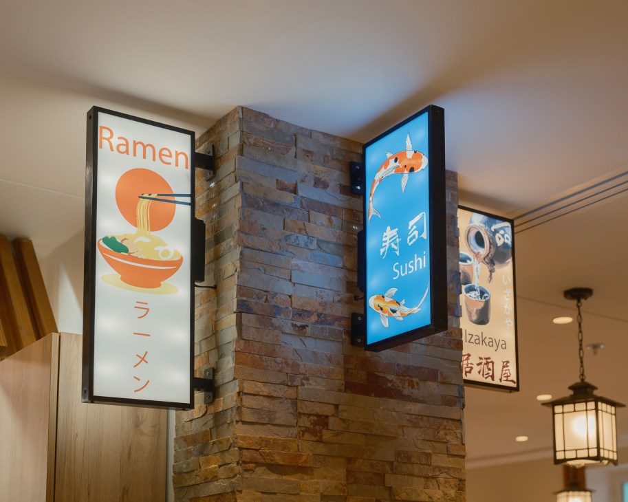 Japanese restaurant signage showing ramen, sushi and izakaya posters on brick wall with traditional lantern lighting