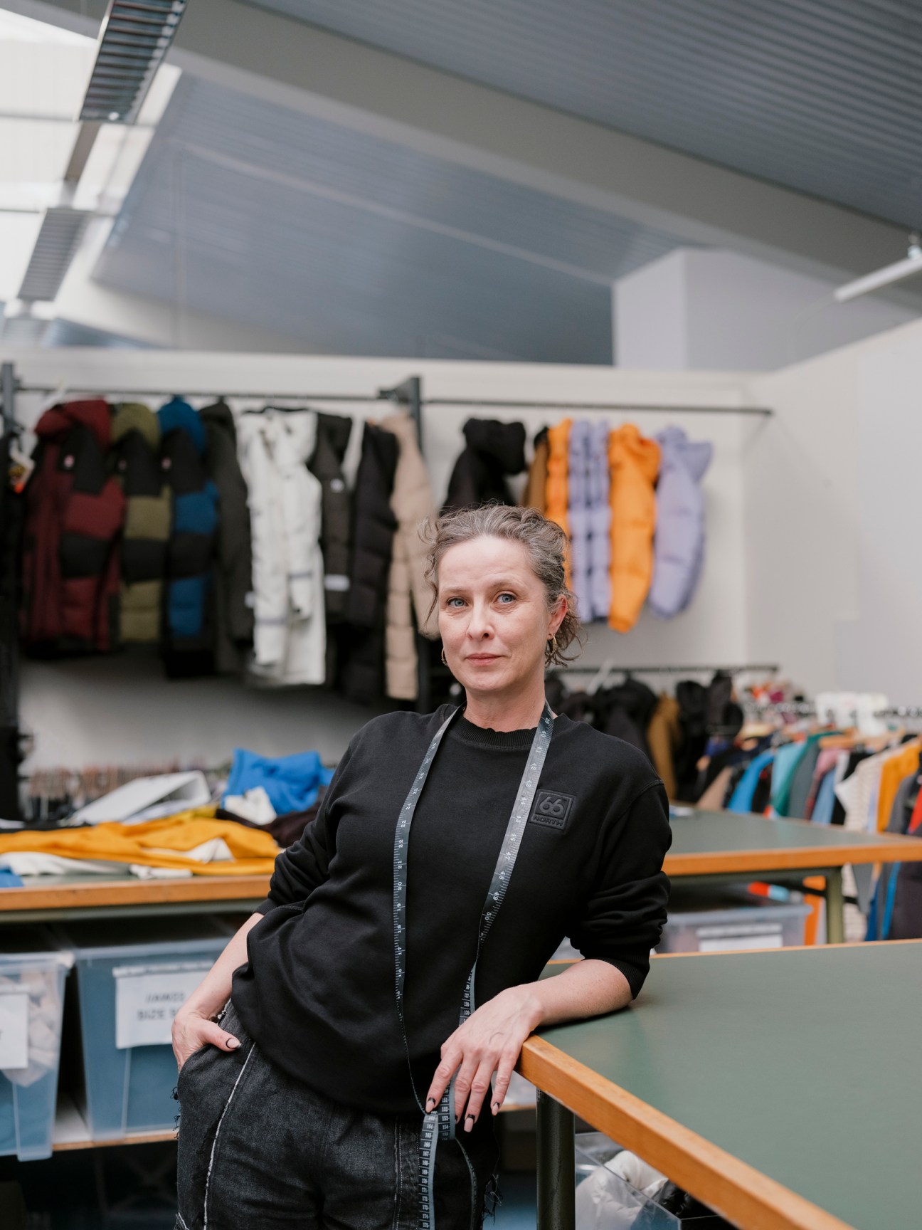 Saeunn Thordardottir, design lead at 66°North, in the brand's showroom with colorful outerwear displayed behind her.