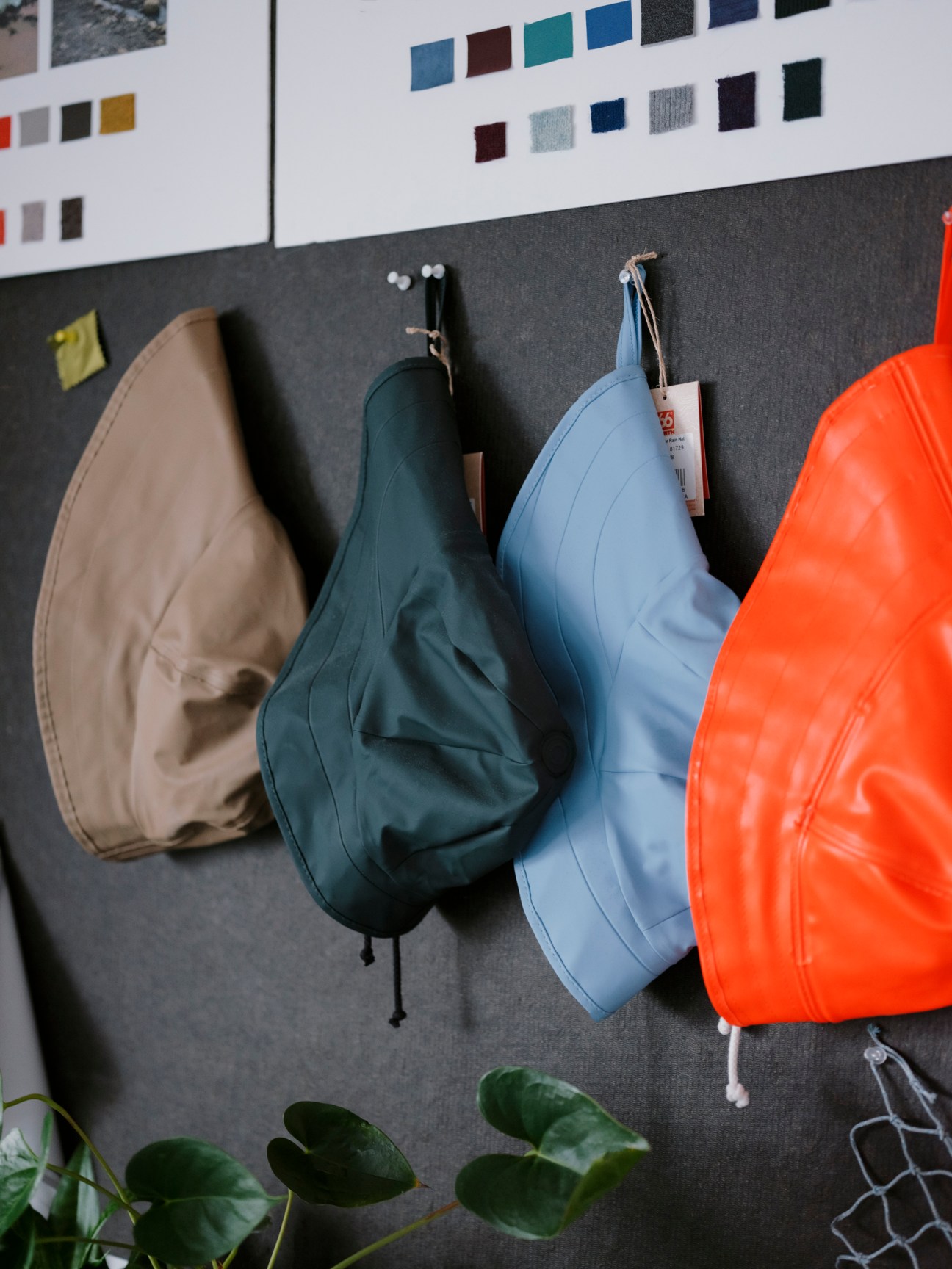 Colorful 66°North puffer jackets and hats displayed on a dark wall with fabric swatches above.