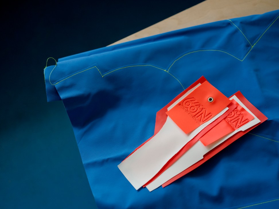 66°North red and white product tags with embossed branding displayed on blue fabric with yellow stitching details.