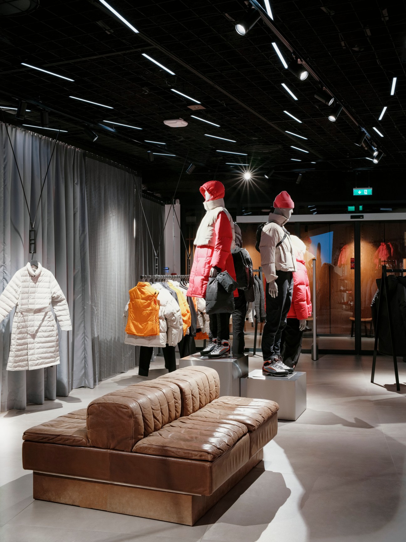 66°North flagship store interior with mannequins wearing colorful parkas and a brown leather bench.
