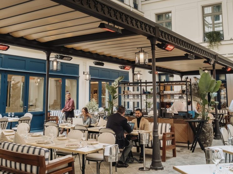Outdoor courtyard dining terrace at La Chambre Bleue with cobblestone floor, awnings, and elegant Parisian architecture