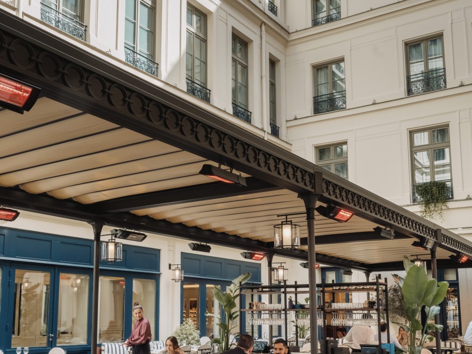 Outdoor courtyard dining terrace at La Chambre Bleue with cobblestone floor, awnings, and elegant Parisian architecture