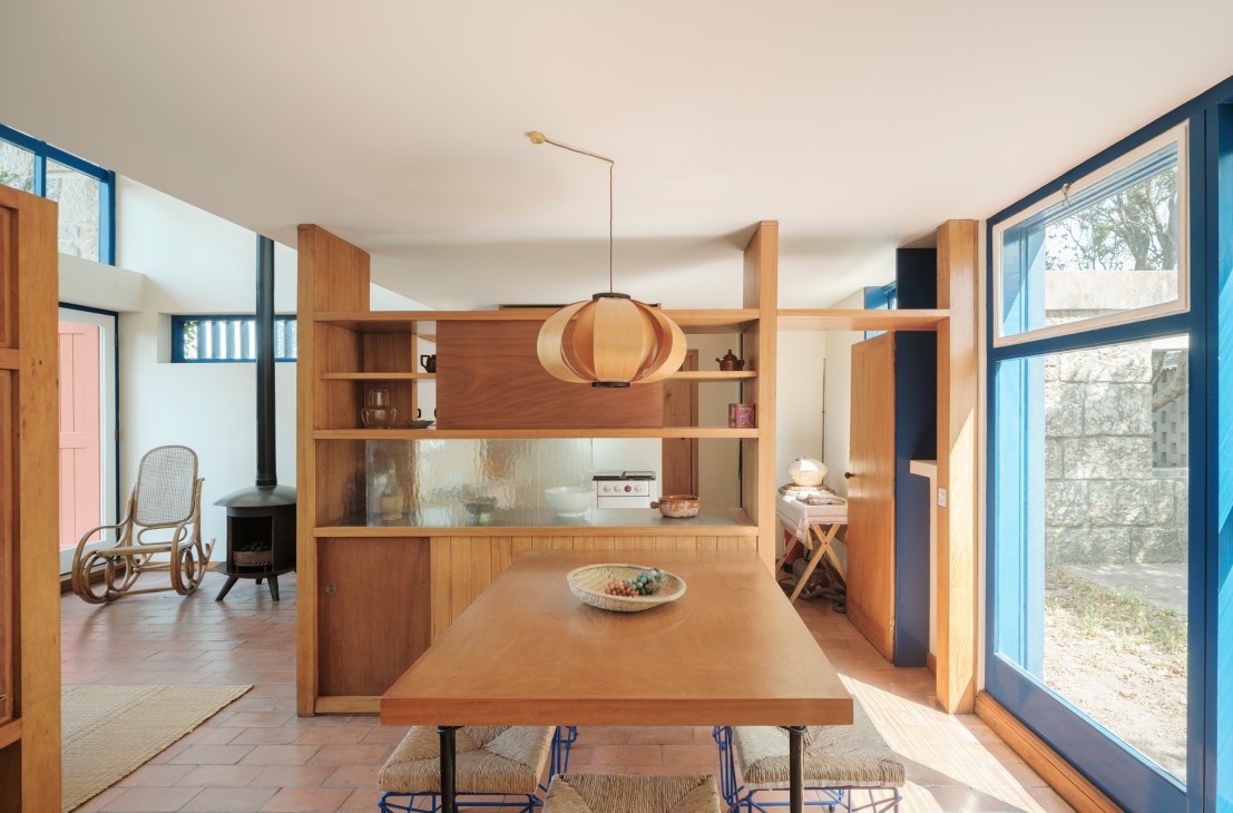 Modern dining room with wood table, built-in shelving, pendant light and large windows