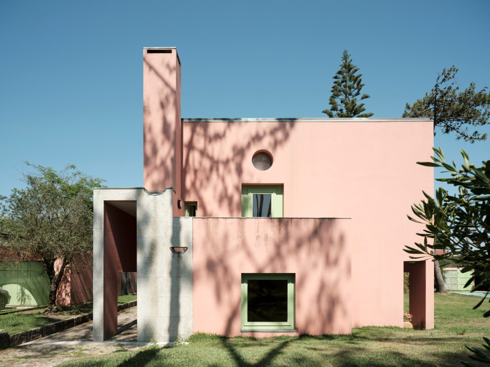 Pink modernist house with green window frames and circular window, featuring tall chimney and geometric design