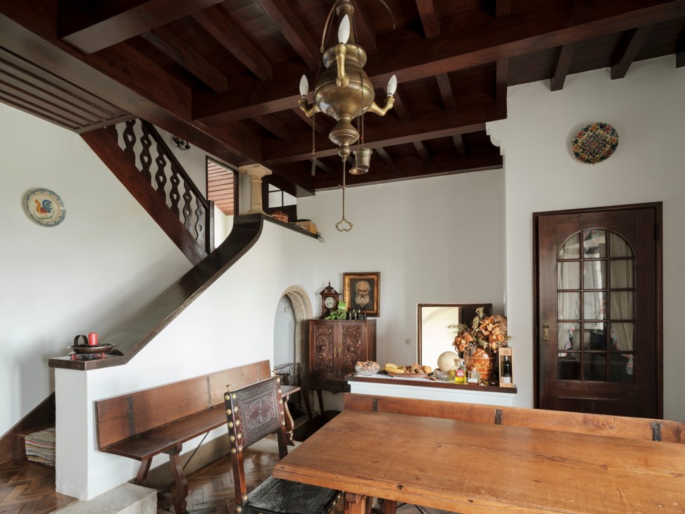 Interior dining room with exposed wooden ceiling beams, brass chandelier, wooden table and traditional Portuguese decor