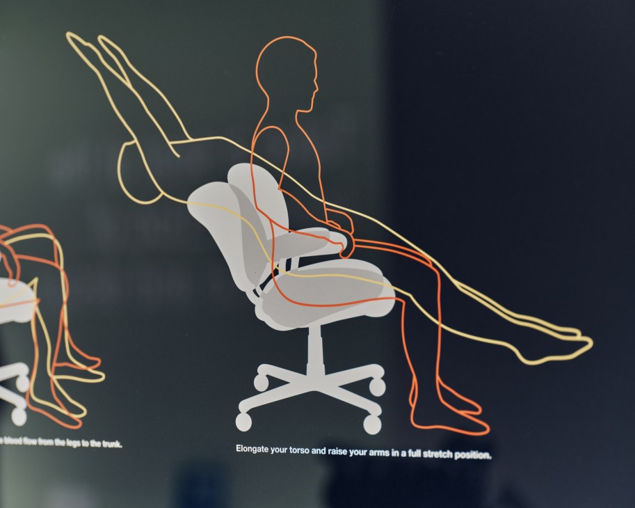 Illustrated diagram showing proper ergonomic sitting position in office chair with arms raised in stretch