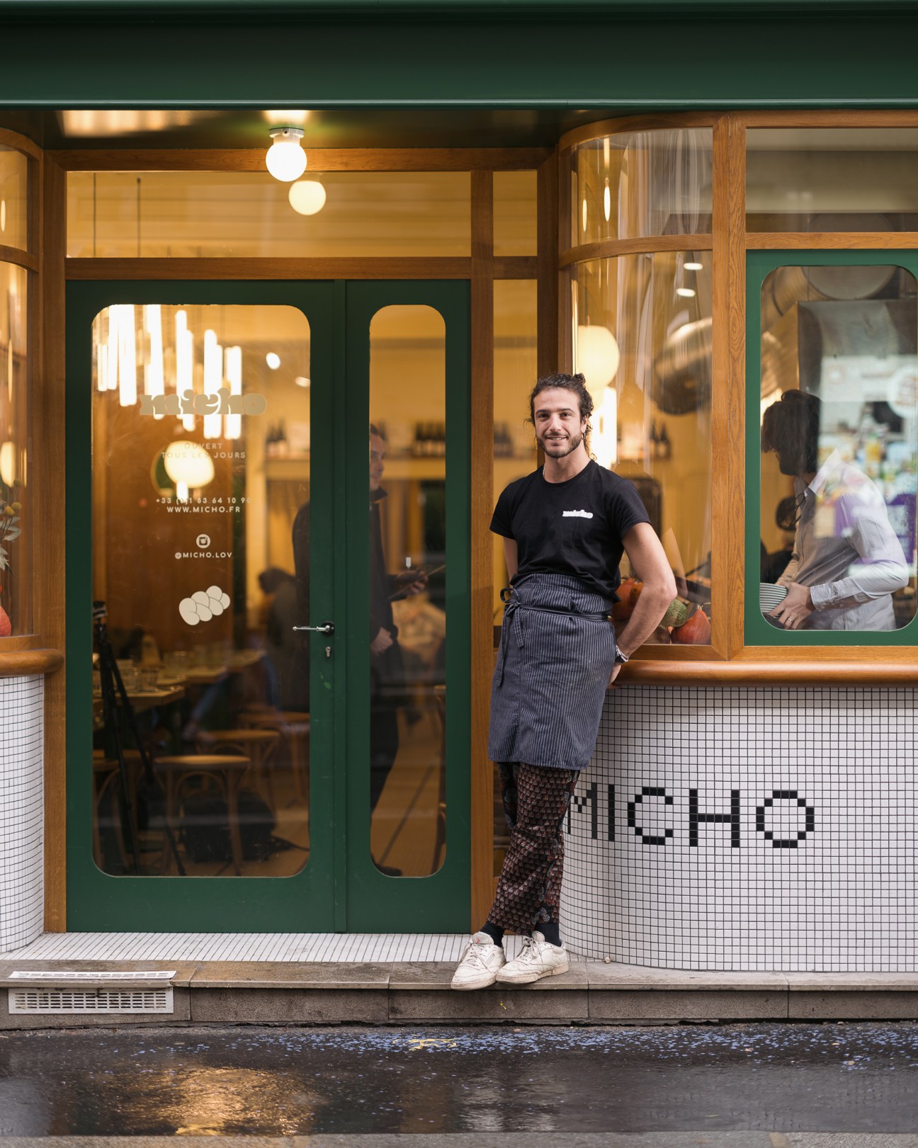 Chef Julien Sebbag standing outside Micho restaurant in Paris with green and white tiled facade