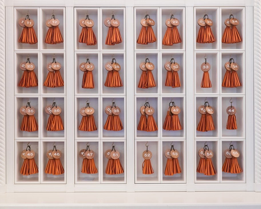 Numbered hotel room keys with orange tassels displayed in white wall-mounted cases.