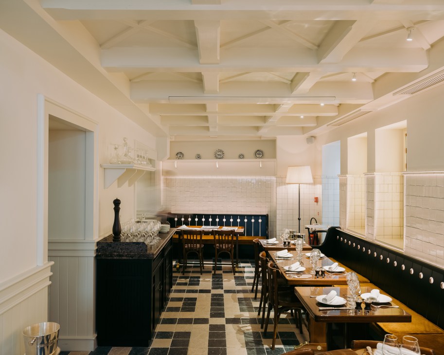 Brasserie Emil dining room with black banquettes, wooden tables, and cream coffered ceiling.