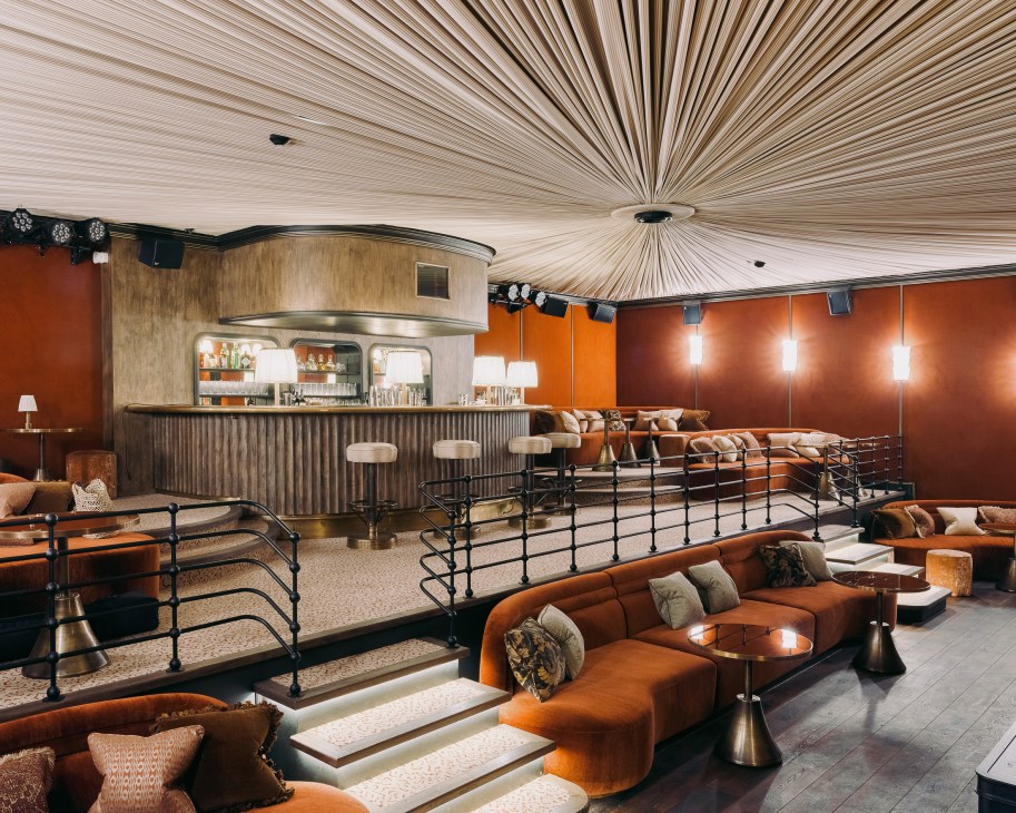 Glamorous cabaret room at Soho House Paris with orange velvet walls, curved seating, and marble pool.