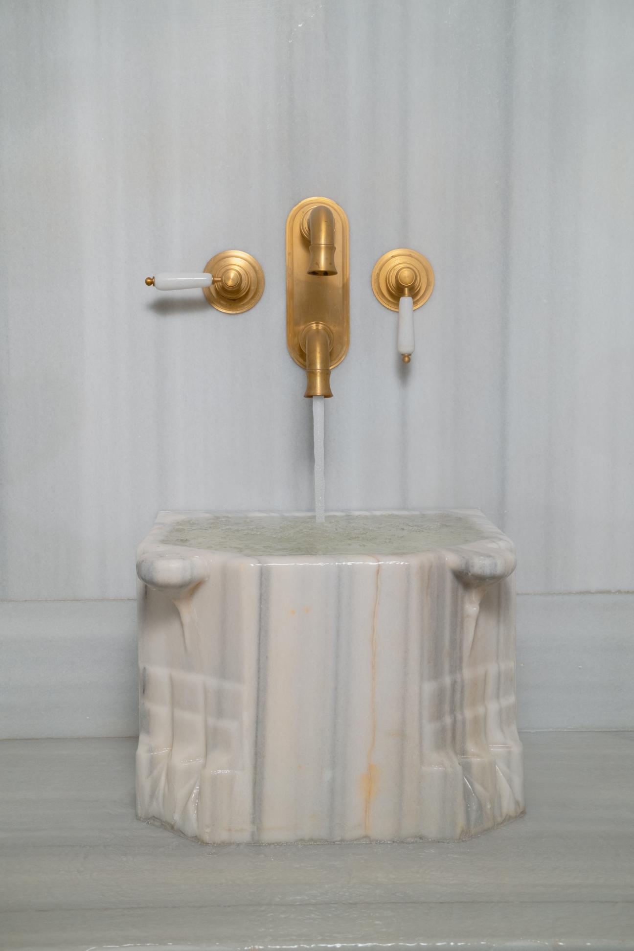 a marble basin with gold-colored faucets