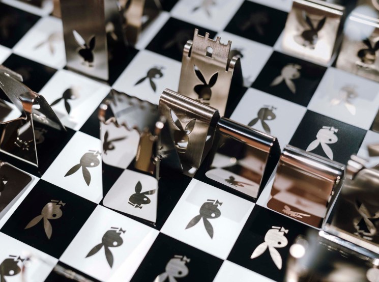 A decorative chess set with metal pieces featuring the Playboy bunny logo on a checkered board.