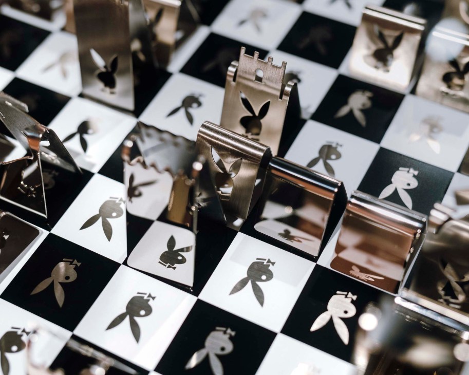 A decorative chess set with metal pieces featuring the Playboy bunny logo on a checkered board.