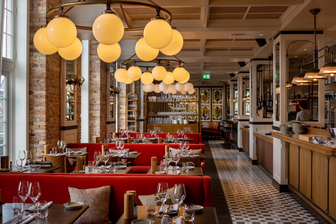 Villa Copenhagen hotel restaurant interior with red banquettes, globe pendant lights and exposed brick columns