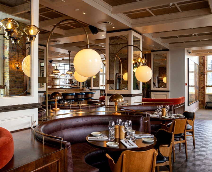 Brasserie Kontrast dining room with curved banquettes, spherical pendant lights, and exposed brick walls