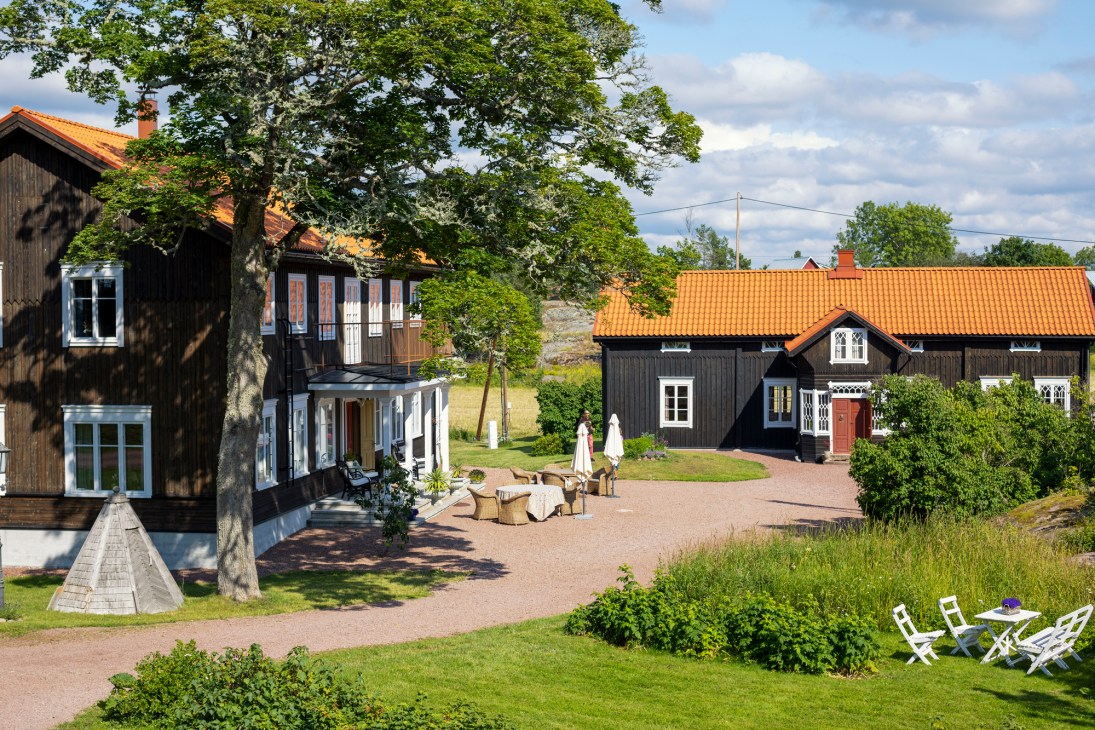 Traditional Scandinavian country house hotel exterior with red wooden siding and white trim surrounded by gardens