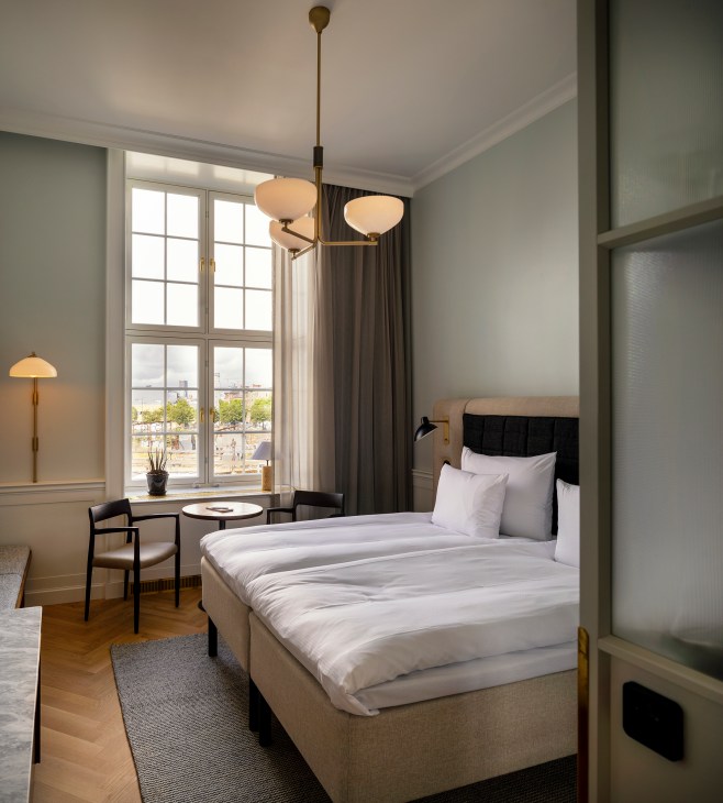 Hotel bedroom with vintage-modern design featuring neutral colors and contemporary furnishings