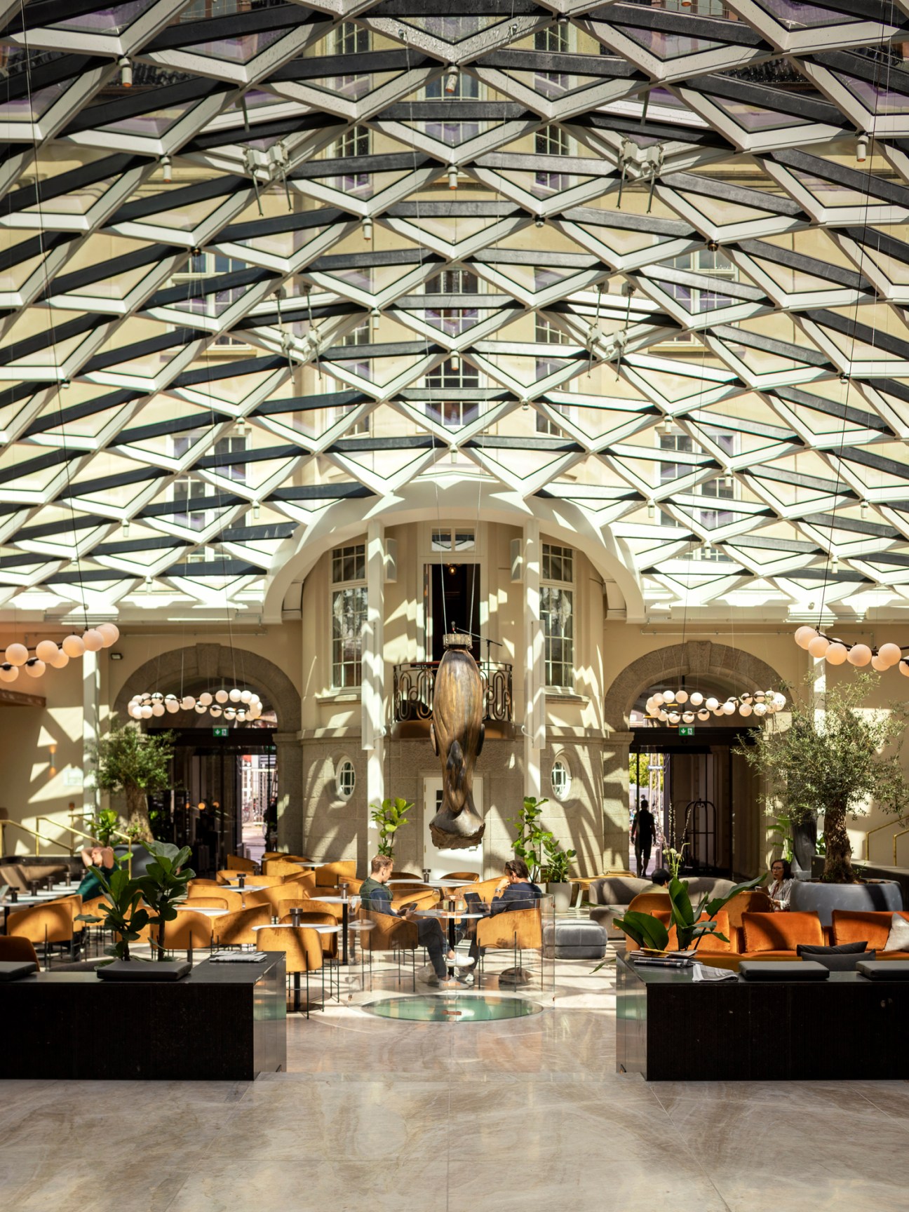 Villa Copenhagen hotel lobby with geometric glass ceiling, ornate cream building facade and modern seating area