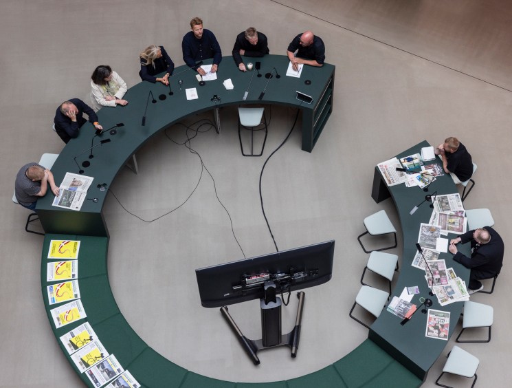 Aerial view of curved meeting table with people working, surrounded by additional seating areas in modern office space