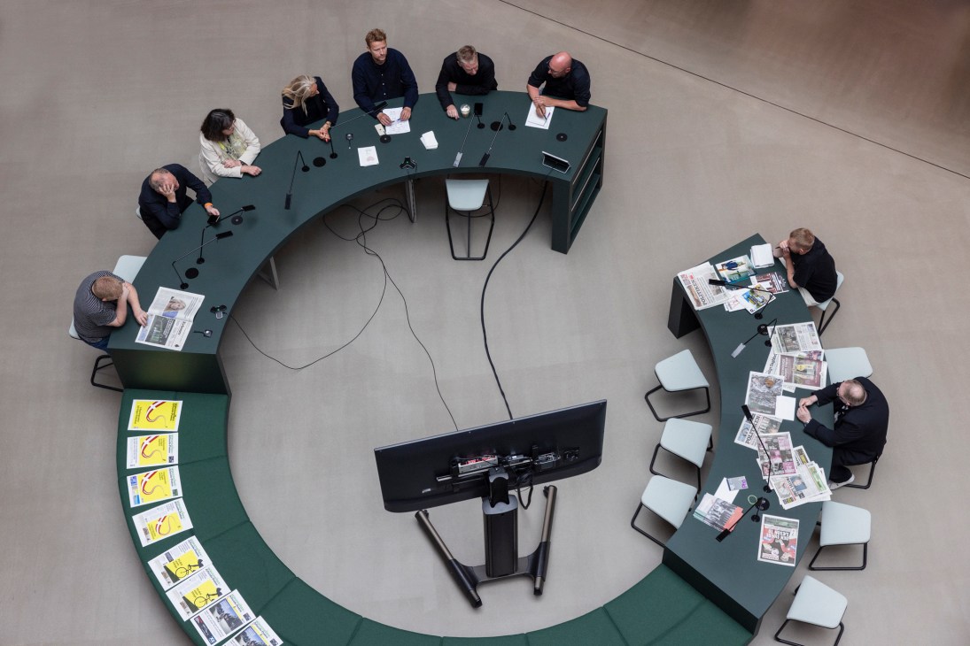 Aerial view of curved meeting table with people working, surrounded by additional seating areas in modern office space
