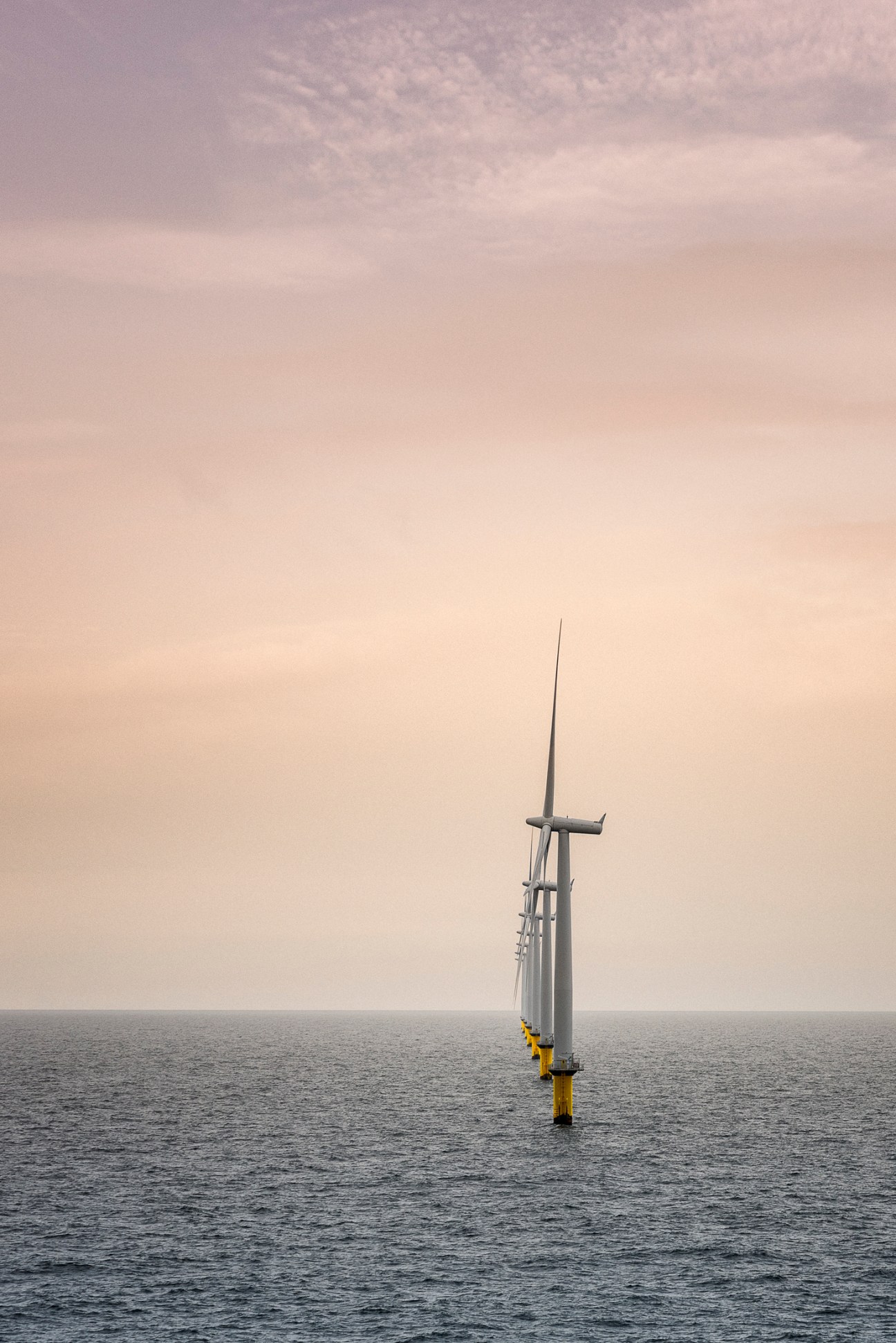 A single offshore wind turbine with yellow base standing in the North Sea.