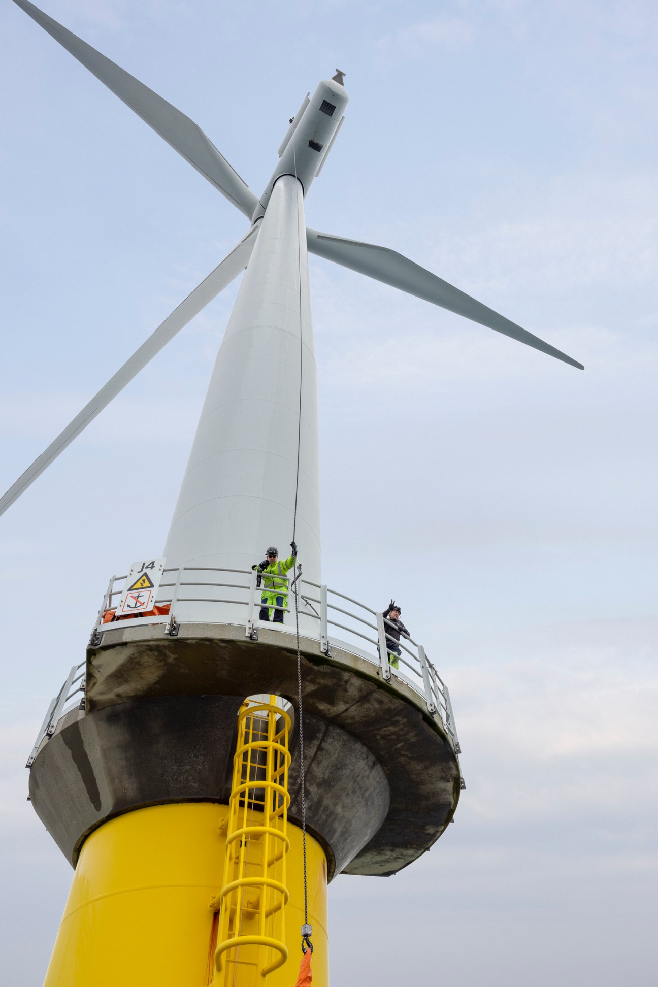 Offshore wind turbine technicians in high-visibility clothing on a maintenance platform