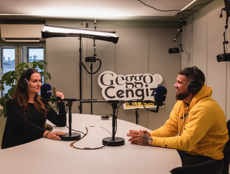 Two people recording a podcast in a professional studio with soundproofing and microphones.