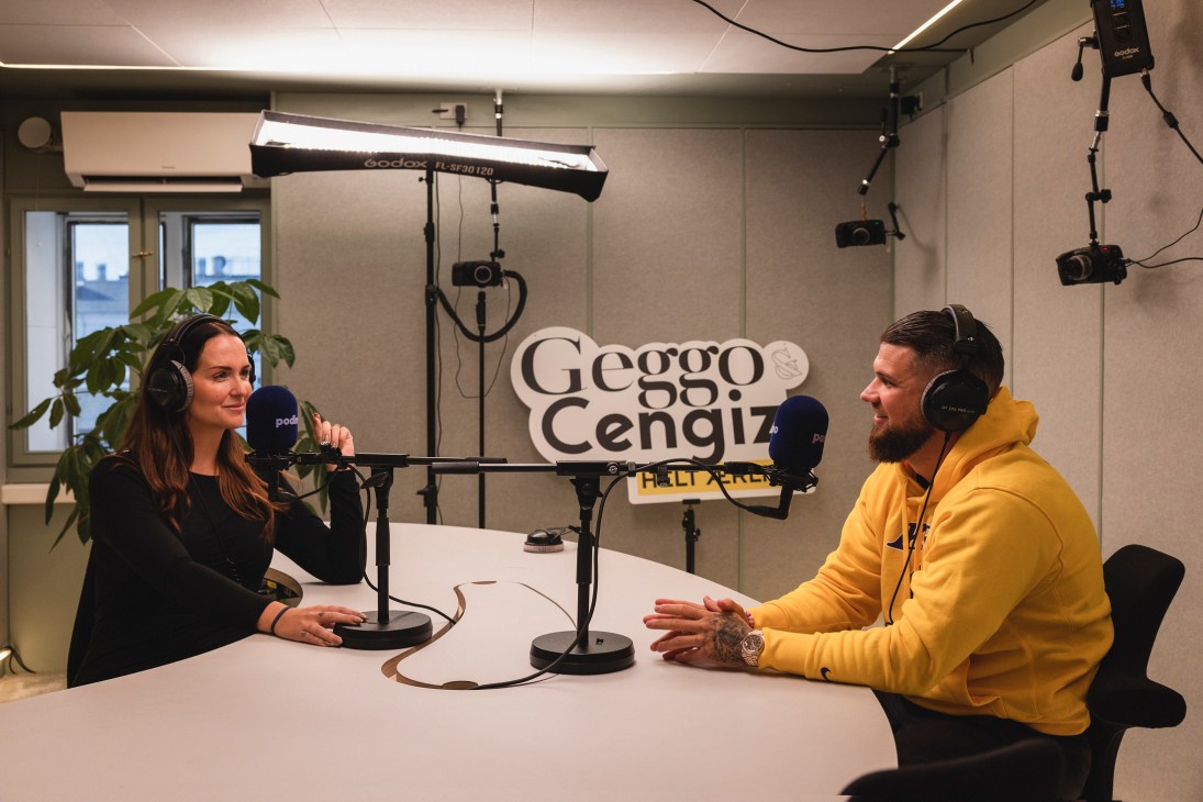 Two people recording a podcast in a professional studio with soundproofing and microphones.