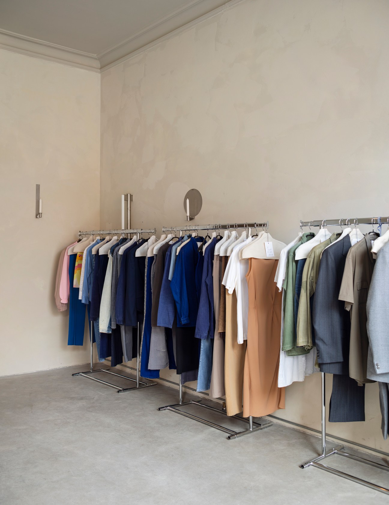 Clothing racks with organized garments in neutral colored interior space