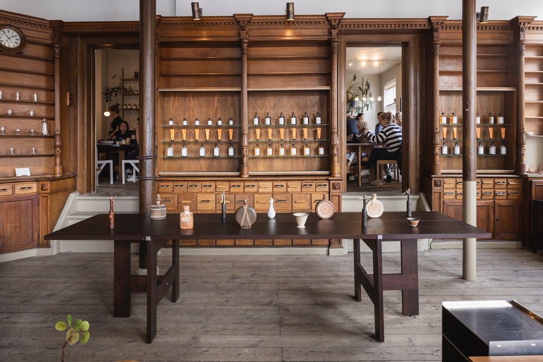Historic pharmacy shelving with wooden drawers and bottles displaying Frama's products in Copenhagen store