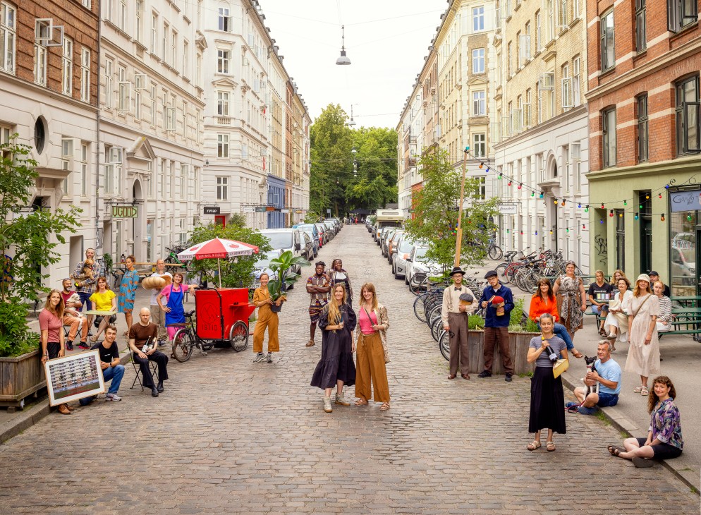 Group portrait of Jaegersborggade residents and business owners standing together on the cobblestone street