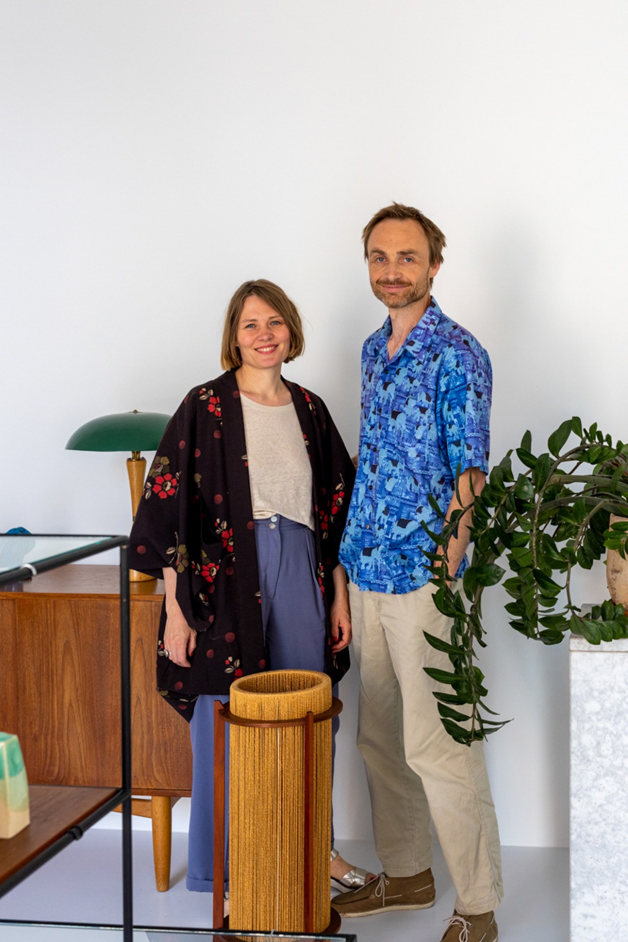 Mia Helmer and Kasper Maaløe standing in Helmer Design & Antik showroom surrounded by vintage Danish furniture
